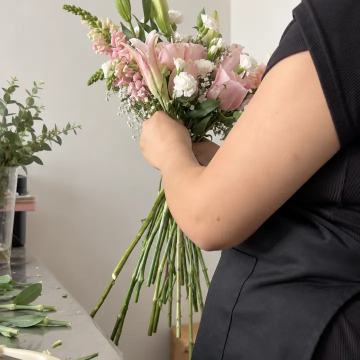 María armando un ramo de liliums en el taller